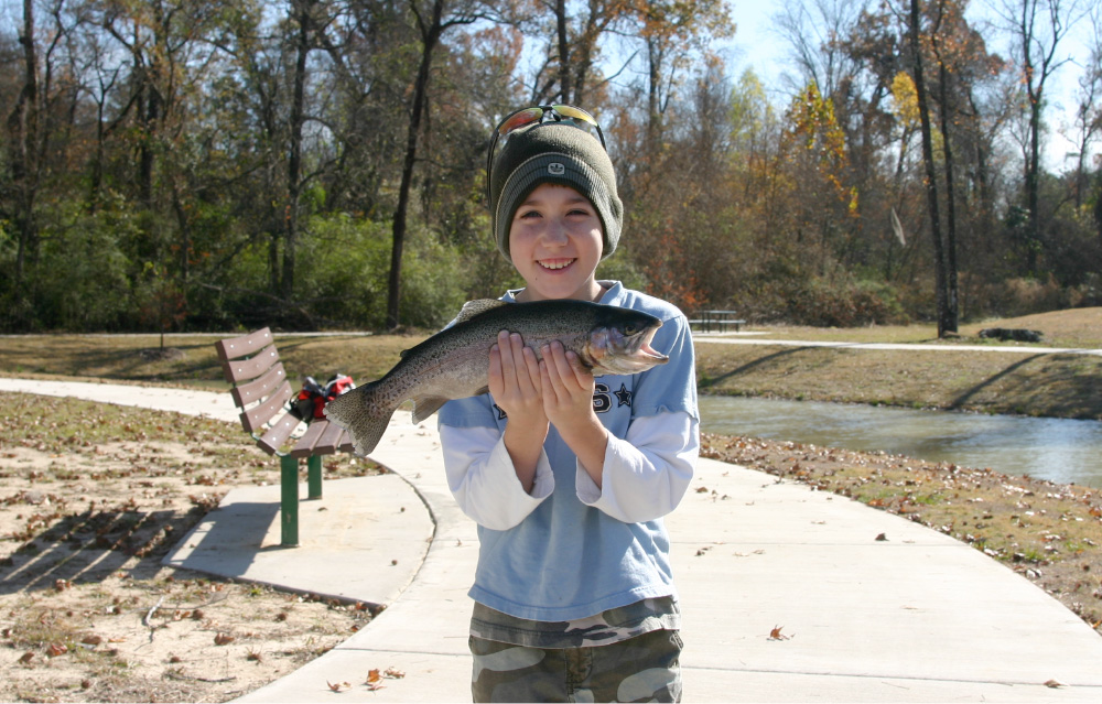 Boy Holding Rainbow Trout in front of him and smiling
