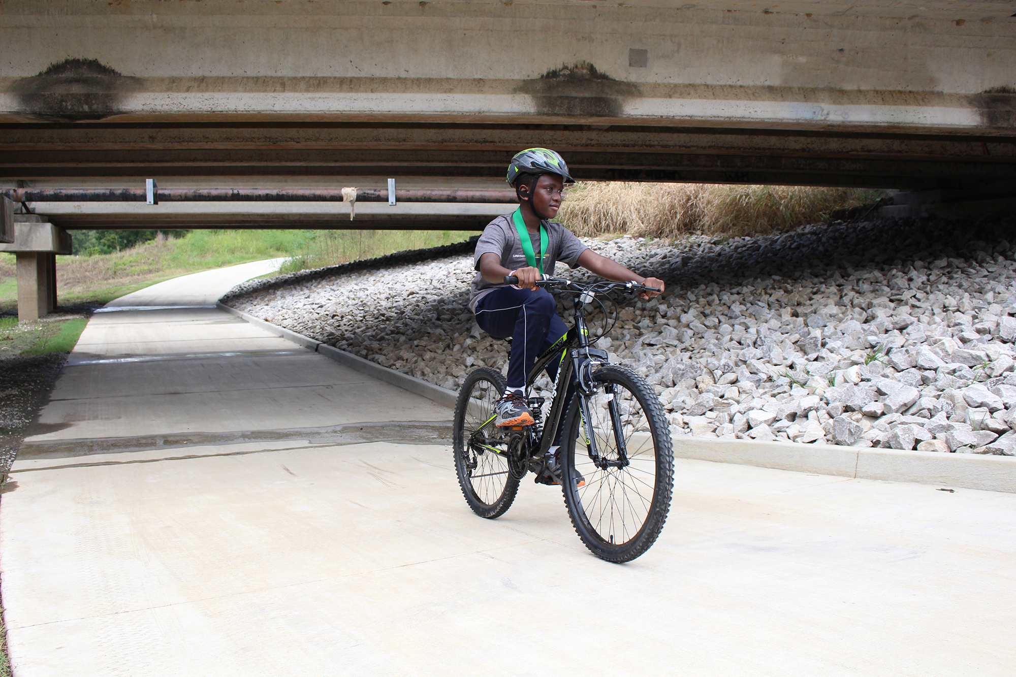 Boy wearing helment and riding bike along cement path